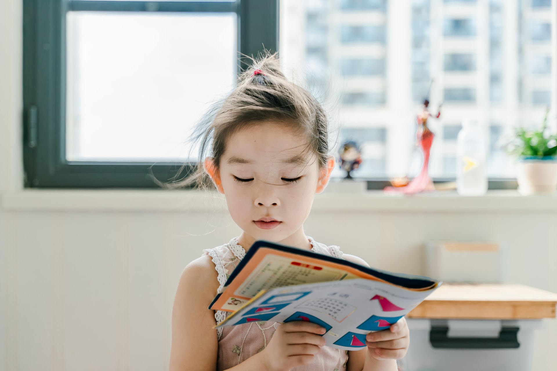 窓辺で読書をする小さな女の子